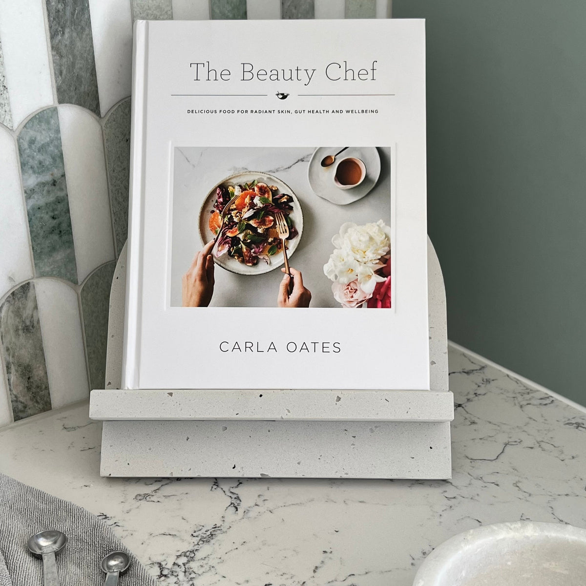 Cookbook Stand in Caesarstone Frozen Terra. Arch shaped and made from quality marble like material. Featuring The Beauty Chef Cookbook by Carla Oates.