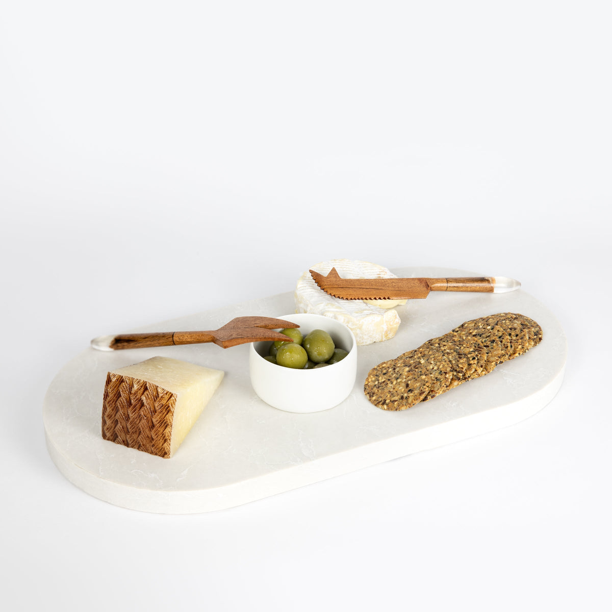 Double arch quartz platters in Caesarstone Alpine Mist™ created by Aureliia Collection. The Double arch quartz cheese boards shown with soft cheese, hard cheese wedge, sicilian olives and grain crackers with timber cheese knifes. An excellent home decor gift for someone who has it all.