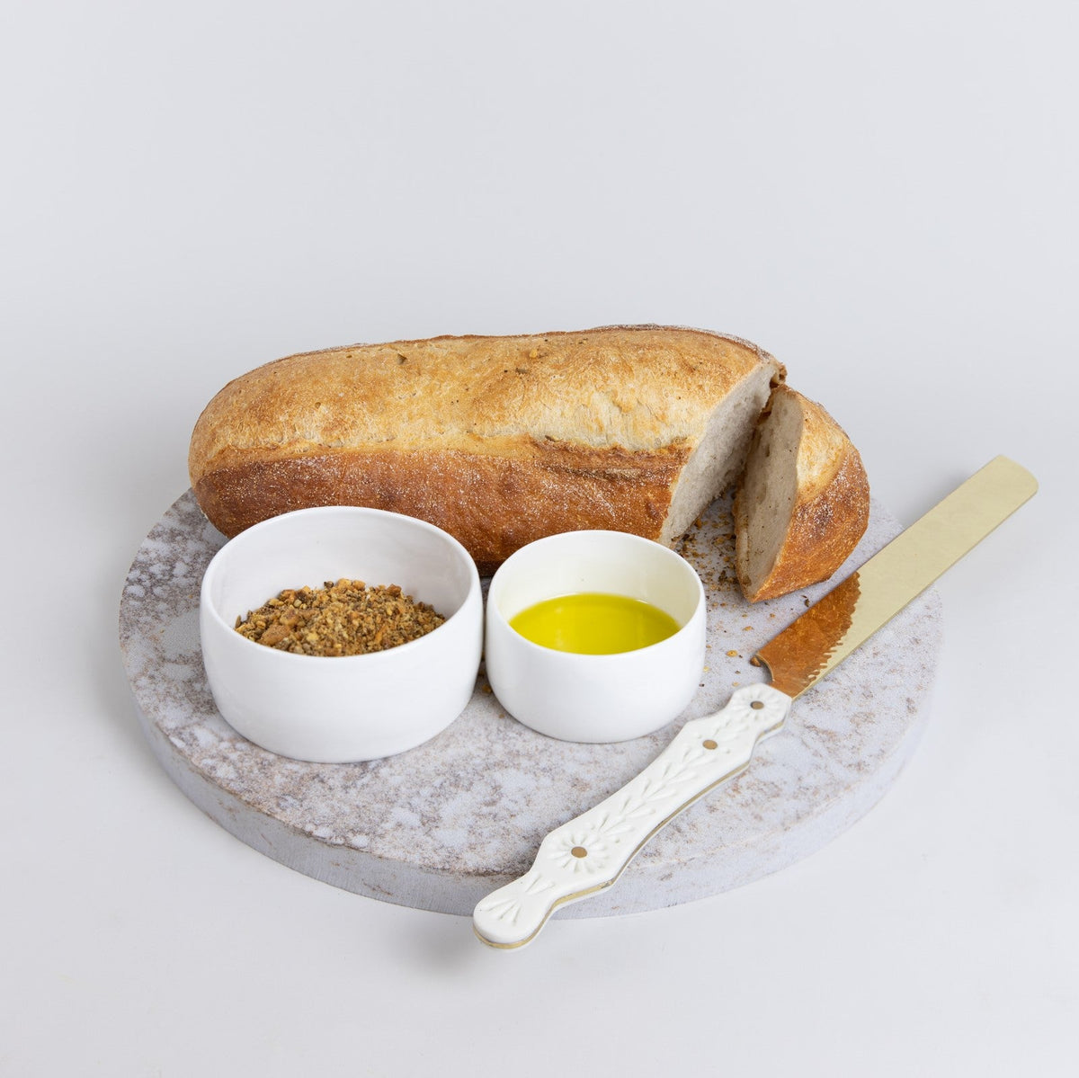 Large Quartz Round Serving Platter in Caeserstone Excava by Aureliia Collection. This serving 30cm round platter is shown styled with fresh baked bread, dukka, olive oil and bread knife. An excellent home decor addition for the avid entertainer. Gift ideas for someone who has everything.