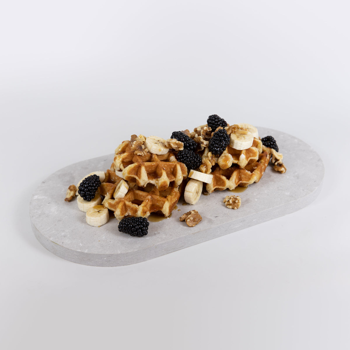 Double arch quartz platters in Caesarstone Clamshell™ created by Aureliia Collection. The Double arch quartz platters shown with waffles, blackberries, banana slices and walnuts drizzled with maple syrup . An excellent home decor gift for someone who has it all.
