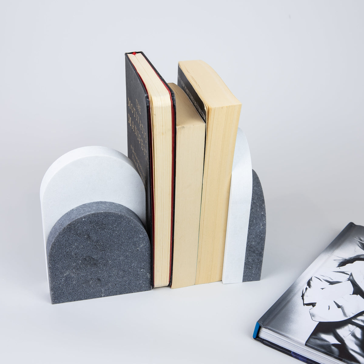 Quartz Bookend Set is 4cm thick. Styled with books. Available in Rugged Concrete partnered with Organic White by Caesarstone with dramatic gradients of robust greys, flashed with white-haze patinas and accentuated with industrial-inspired imperfections, meets a clean white surface with subtly blended undertones, reflecting a natural appearance that is effortlessly chic. The perfect addition to your home decor, similar to marble bookends.