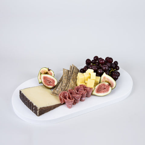 Double arch quartz platters in Caesarstone Aterra Blanca created by Aureliia Collection. The Double arch quartz charcuterie boards shown with hard cheese wedge, red grapes, figs, salami river and grain crackers. An excellent home decor gift for someone who has it all.