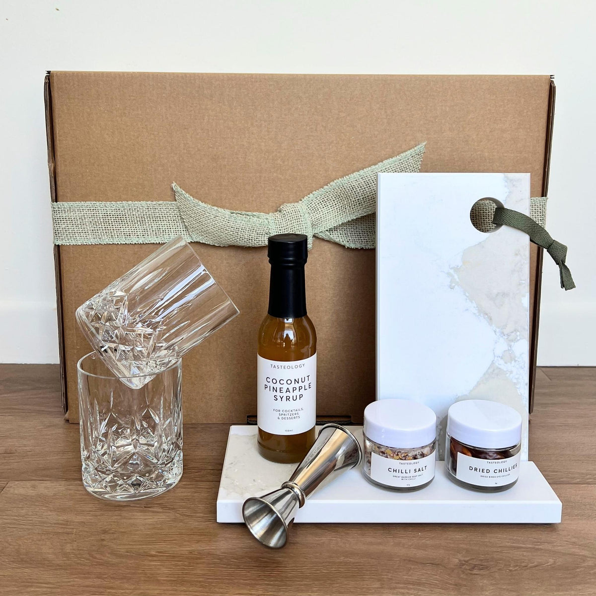 Sip back and chill-ax. Gift box with DStill diamond cut old fashion glasses, Tasteology Chilli Tropical Cocktail Kit, Jigger, Cocktail Stand and Prep Board from Caesarstone Calacatta Maximus with the look and feel of marble.