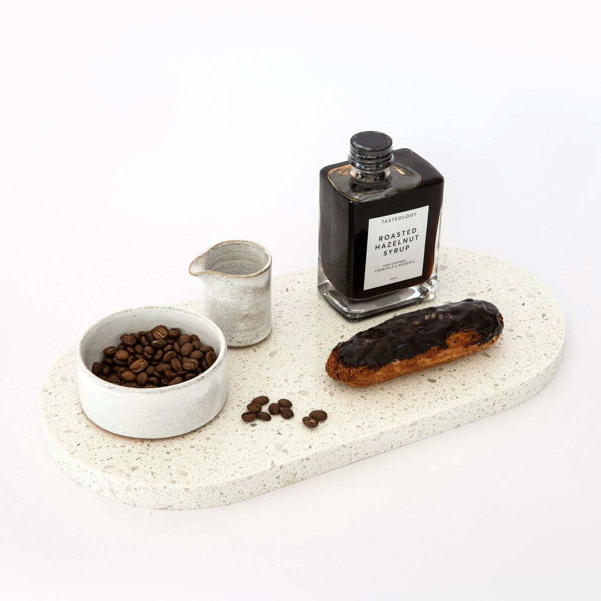 Double arch quartz platters in Caesarstone Nougat™ created by Aureliia Collection. The Double arch quartz dessert platter shown with chocolate éclair, coffee beans and Tasteology hazelnut syrup. An excellent home decor gift for someone who has it all.