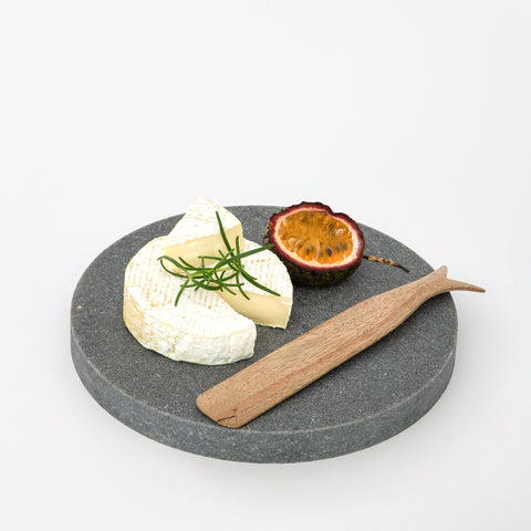 Quartz round small serving platter in Caesarstone Rugged Concrete™ created by Aureliia Collection. Similar to a round marble tray, only more durable than marble. The Small Quartz Round Serving Platter shown with soft cheese, cut passionfruit and timber cheese knife. Making a great small cheese board. An excellent home decor gift for someone who has it all.