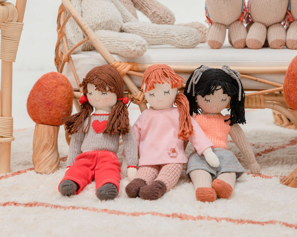 Three beautiful handmade dolls sit next to a toadstool
